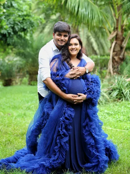 An outdoor couple's portrait surrounded by lush greenery. The vibrant blue of her gown stands out beautifully against the natural backdrop, creating a striking and romantic image.