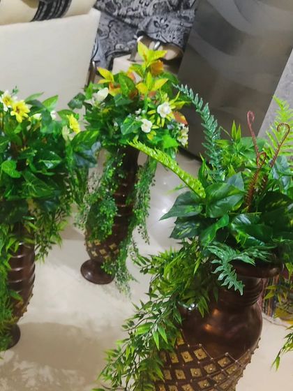 A collection of three vase arrangements with different types of artificial greenery and some small flowers. Grouping them together creates a fuller, more impactful display.