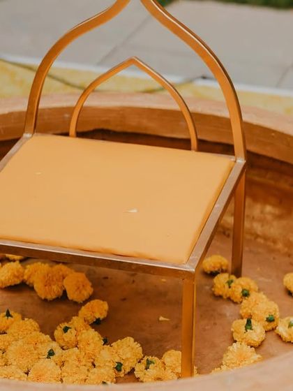 A close-up of the custom seating we designed for a Haldi ceremony. The small, elegant chair is placed inside a large terracotta urli, ready to be filled with marigold petals for the ritual.