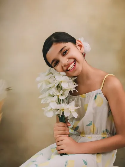 A beautiful, smiling portrait of an older girl holding a bouquet of white flowers, her happiness shining through.