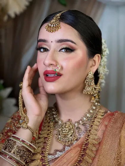 The beauty of a South Indian bride is timeless. This look focuses on classic elements: bold, expressive eyes, a rich red lip, and traditional gold temple jewelry, all coming together to create an aura of divine grace.