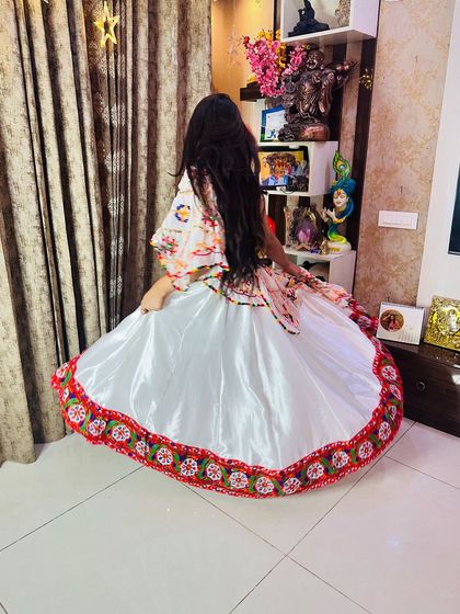 A back view of the white satin lehenga, showing the full flare of the skirt and the beautiful embroidered border.