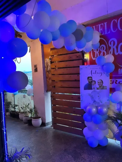 The entrance to the elephant-themed birthday party, decorated with a simple blue and white balloon arch and a welcome standee featuring a family photo.