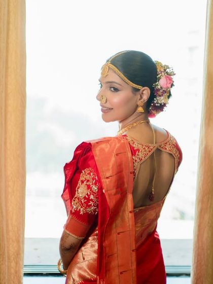 A back shot of the bride, showcasing the elegant hairstyle with fresh flowers and the beautiful design of her blouse. My team ensures every detail is perfect.