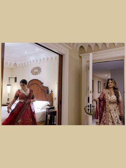 A candid moment of the bride getting ready, seen from the doorway by her sister or friend.