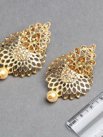 A product shot of our golden filigree earrings, with a ruler to show their size. These are delicate, lightweight, and intricately designed.