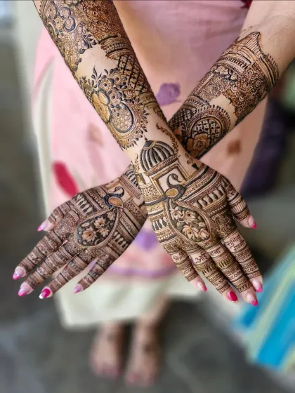 A full view of the custom bridal mehendi, combining personal names and modern skylines with traditional peacock and lotus designs.
