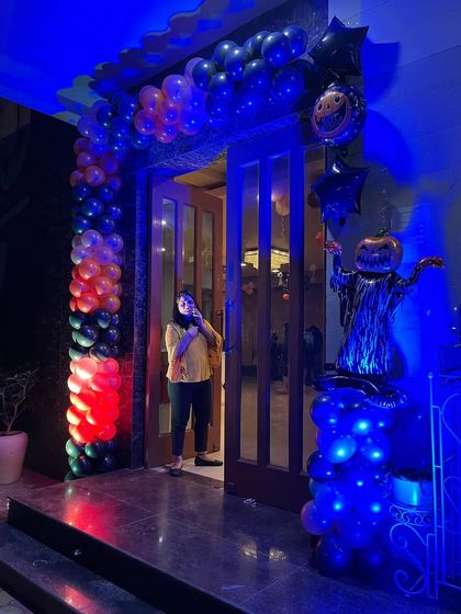 I can decorate the entire venue for your themed party. This Halloween entrance features a balloon column in spooky colors, a lighted pumpkin scarecrow figure, and dramatic blue lighting to set a fun and eerie mood right from the door.