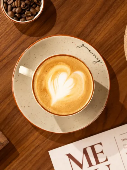 A top-down shot of a cappuccino at Gremy, with the branded plate and menu creating a cohesive brand image.