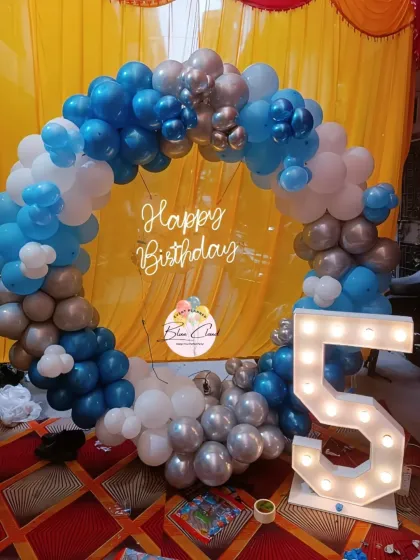 A blue, white, and silver balloon ring with a neon sign and marquee number '5'.