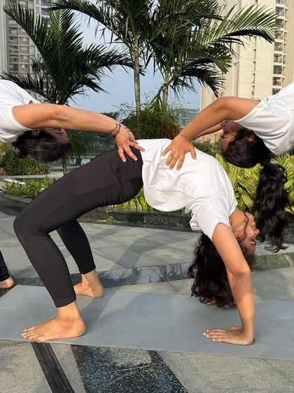 A trio of students supports each other in a creative backbend formation. This kind of partner work not only builds physical strength but also deepens the bonds within our yoga family.