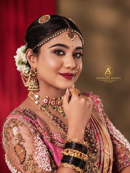 The unmatched glow of a bride. This portrait focuses on the rich pink saree and the contrast with the black bangles, a classic combination in South Indian weddings.