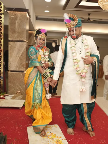 A beautiful moment from the Saptapadi ritual. The bride's traditional yellow Nauvari and teal blouse are perfectly complemented by her glowing makeup and classic jewellery.