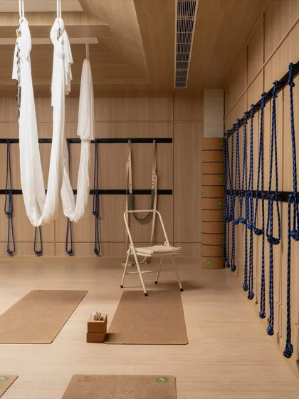The aerial yoga setup, where the white silks provide a soft contrast to the warm wood of the studio.