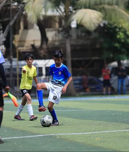 A player sets up for a free-kick, with the referee looking on.