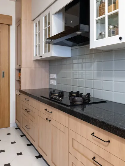 This kitchen combines classic elements for a warm, nostalgic feel. The black and white floor tiles, light wood shaker cabinets, and subway tile backsplash create a timeless and inviting atmosphere.