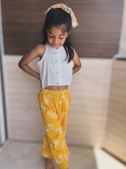 Sunshine in an outfit! This set pairs a simple white crop top with vibrant yellow floral pants. It's a cheerful and breezy combination for warm days.