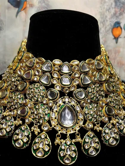 A close-up of a heavy bridal Kundan choker. The sheer density of the uncut stones and the green enamel work make this a truly extravagant piece.
