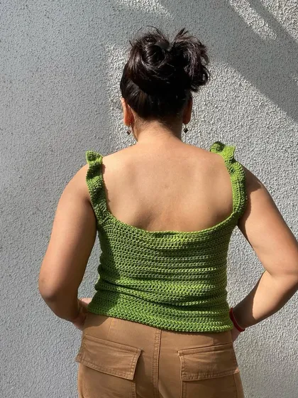 The back of the green ruffle top features a simple, clean design with a scoop back, making it easy and comfortable to wear.