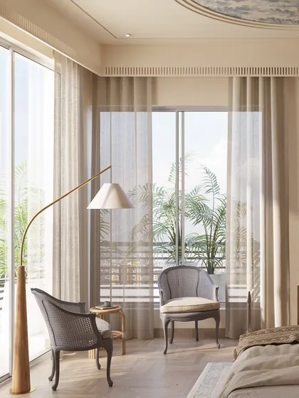Large windows flood this bedroom with natural light, highlighting the serene color palette and classical furniture. A pair of elegant chairs creates a quiet seating area, perfect for enjoying the view and a moment of peace.