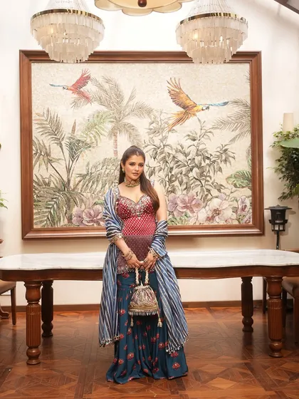 A full view of a stunning festive look, complete with a heavily embroidered potli that adds a touch of traditional glamour to the colourful outfit.