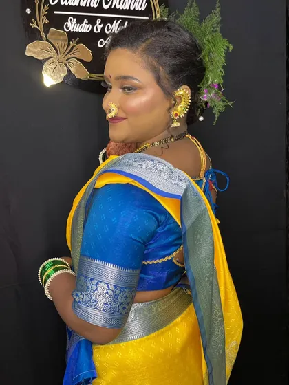 A side profile of the model, showcasing the seamless blend of the foundation and the beautiful floral hairstyle that complements the traditional look.