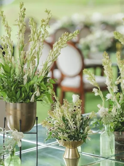 Simple, elegant centerpieces of white tuberoses in brass pots, perfect for a classic and timeless wedding decor theme.