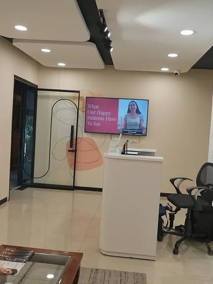 A wider view of our Lajpat Nagar reception, where you can often see patient testimonials playing on the screen.