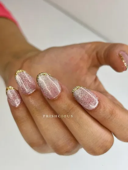 When golden French elegance meets pink cat eye magic. This beautiful design combines a glittery gold French tip with a shimmery pink cat eye base.