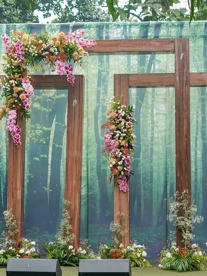 A unique photobooth with a forest-print backdrop and rustic wooden frames adorned with beautiful orchids and wildflowers.