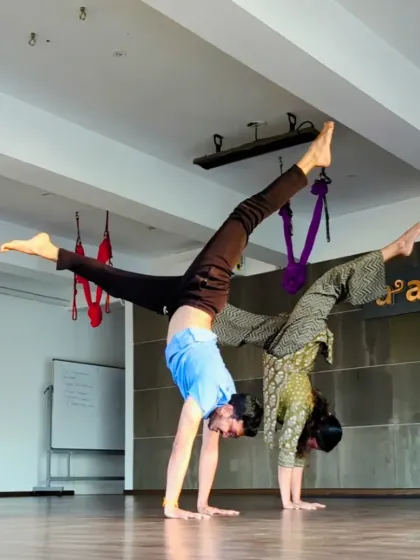 Two practitioners hold a synchronized split-leg handstand, showcasing the strength and artistry of the practice.