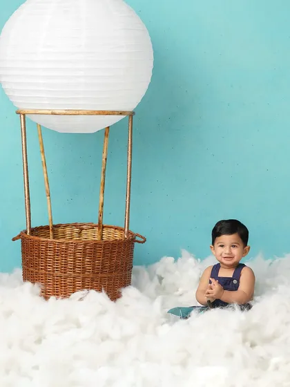 This little explorer is ready for an adventure in his hot air balloon. The simple setup with cotton clouds and a wicker basket creates a world of imagination.