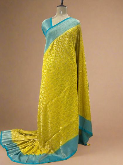A beautiful yellow soft crepe saree with a contrasting blue border and jaal weaving.
