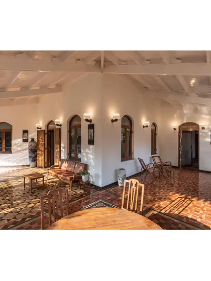 The restored veranda, where sunlight plays across the original geometric tile flooring. We focused on reviving these transitional spaces to create a seamless connection between the historic interiors and the natural surroundings, blending colonial and vernacular influences.