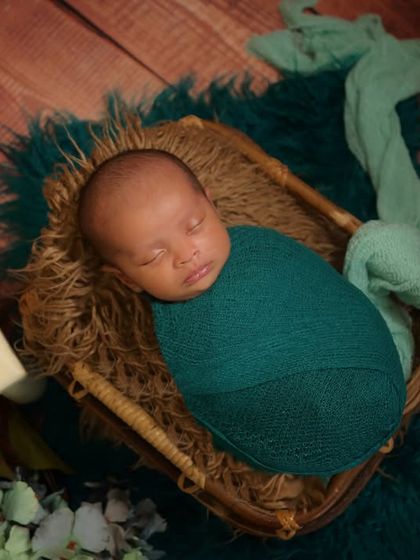 A newborn sleeps peacefully in a basket, with a wooden calendar block marking the date. This is a wonderful way to commemorate their birth date in a photo.