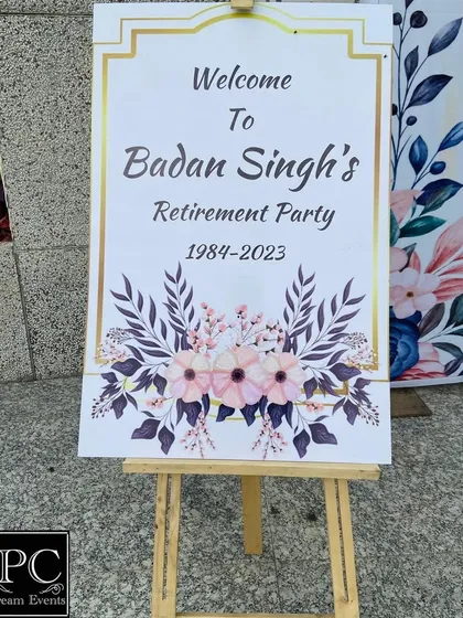 A welcome sign for the retirement party. The elegant design with a gold frame and floral motifs provides a warm and formal welcome to all the guests attending the celebration.