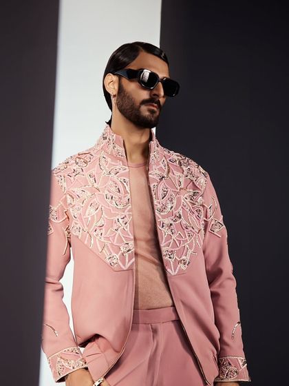 A detailed shot of the dusty rose bomber jacket. The embroidery is dense and textural, creating a rich pattern across the yoke and shoulders. It is a perfect piece for a summer event.