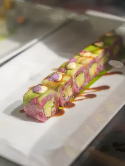 A vibrant pink sushi roll filled with fresh avocado, showcasing our playful and artistic approach to global cuisine.
