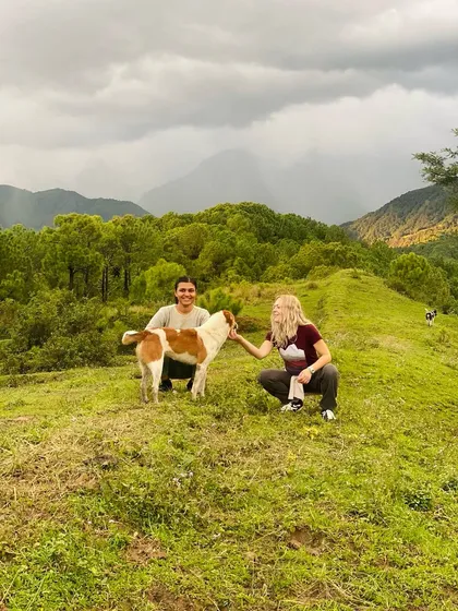Even our four-legged friends join in the spirit of connection and joy. Two participants share a moment with a friendly local dog on a hillside in Palampur.