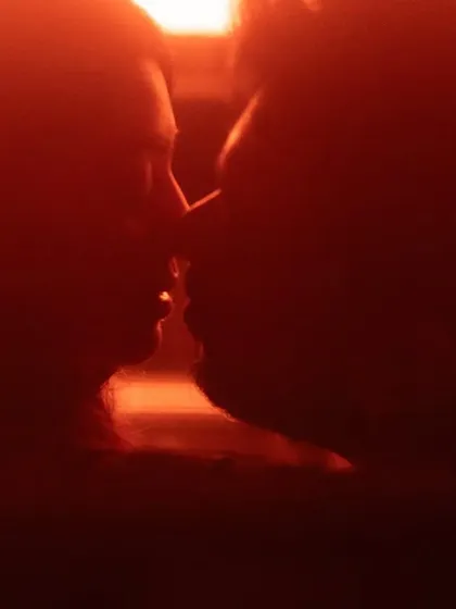 An intensely close-up silhouette in a deep red hue. This abstract and passionate shot focuses on the proximity and connection between the couple, suggesting a deep, unspoken bond.