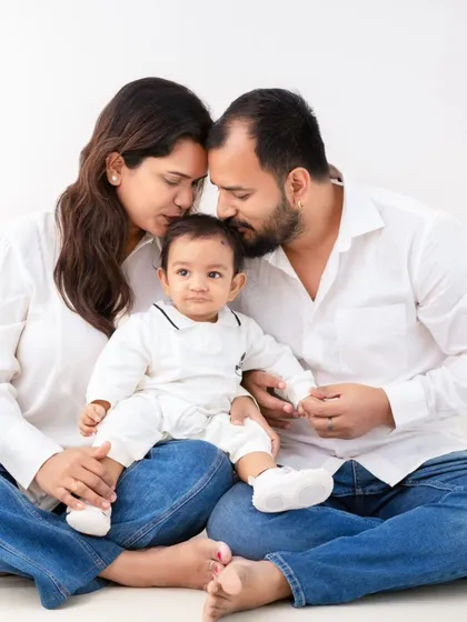 A moment of quiet intimacy. In a simple setting of white shirts and jeans, this family shares a tender forehead kiss, a beautiful, unposed expression of their bond.