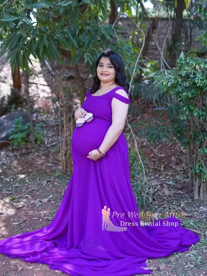 This purple flowy gown is perfect for an outdoor shoot, shown here with tiny baby shoes as a sweet prop. The dress's simple elegance and long train provide a beautiful backdrop for celebrating your growing family.