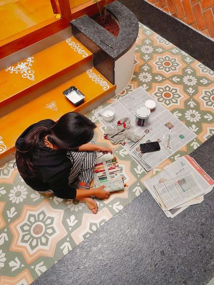 The workspace for the Alpona project, with my paints and tools ready. This kind of detailed floor painting is a unique way to customize a home.