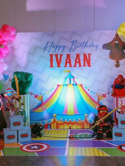 Another view of the Superhero Carnival party, showing the full stage with a mix of hero cutouts and a colorful circus tent backdrop.