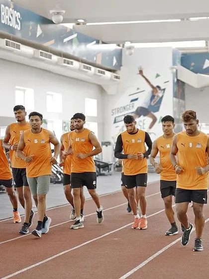 The team warming up with a light jog on the indoor track. Every session starts with a structured plan to prepare the body for the work to come.