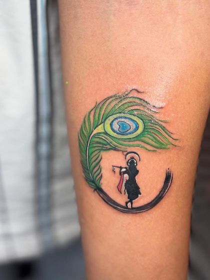 A closer look at the vibrant color and detail in this Krishna and peacock feather tattoo. The colors are chosen to be bright and long-lasting.
