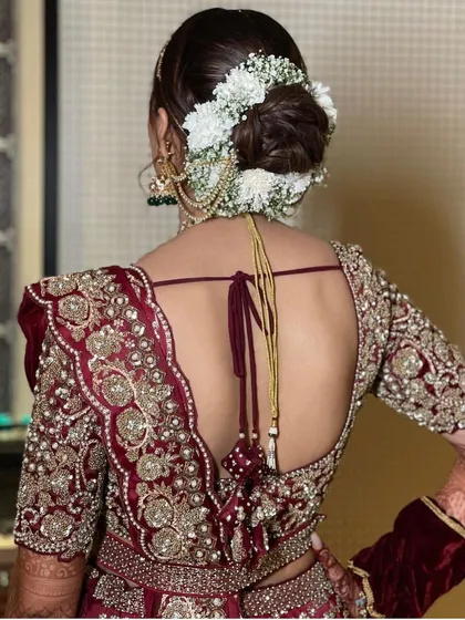A side view of the white floral gajra bun, highlighting how it complements the bride's jewellery and the intricate embroidery of her blouse.