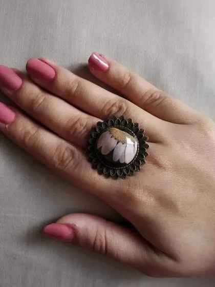 This is a beautiful daisy ring with a vintage-inspired dark metal setting. The white and yellow daisy is perfectly preserved under a clear resin dome, creating a lovely piece of floral jewelry.