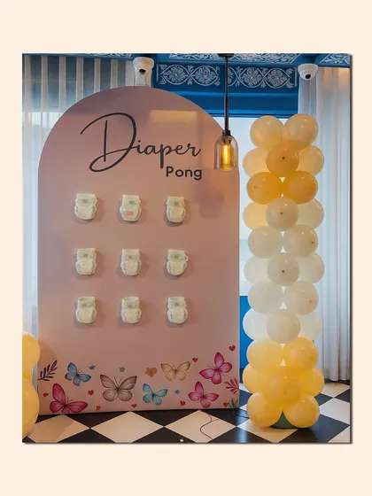 It's not a baby shower without some fun. We designed this custom "Diaper Pong" game station, complete with a themed backdrop and matching balloon decor, to get guests laughing and mingling.