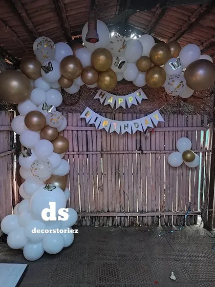 We decorated this rustic bamboo hut for a birthday party using a white and gold balloon arch. The 'Happy Birthday' banner and butterfly details complete the charming and celebratory look.